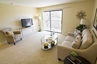 A bright and modern living room with a comfortable sofa, a TV, and a coffee table next to a sliding glass door.