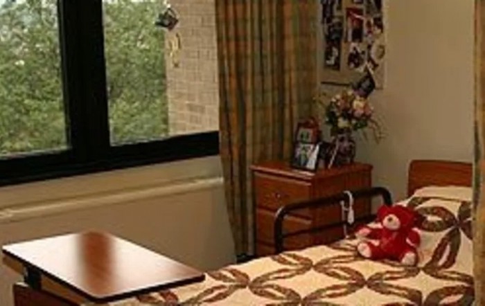A cozy dorm room with a bed, window, and personal decorations.