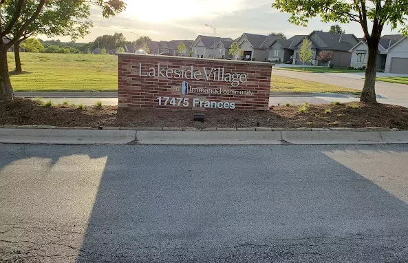 A brick sign at the entrance of a suburban housing community displaying the name and address.