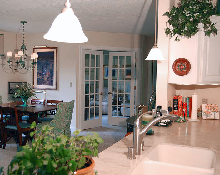 A cozy kitchen interior with a dining area, featuring plants and warm lighting.