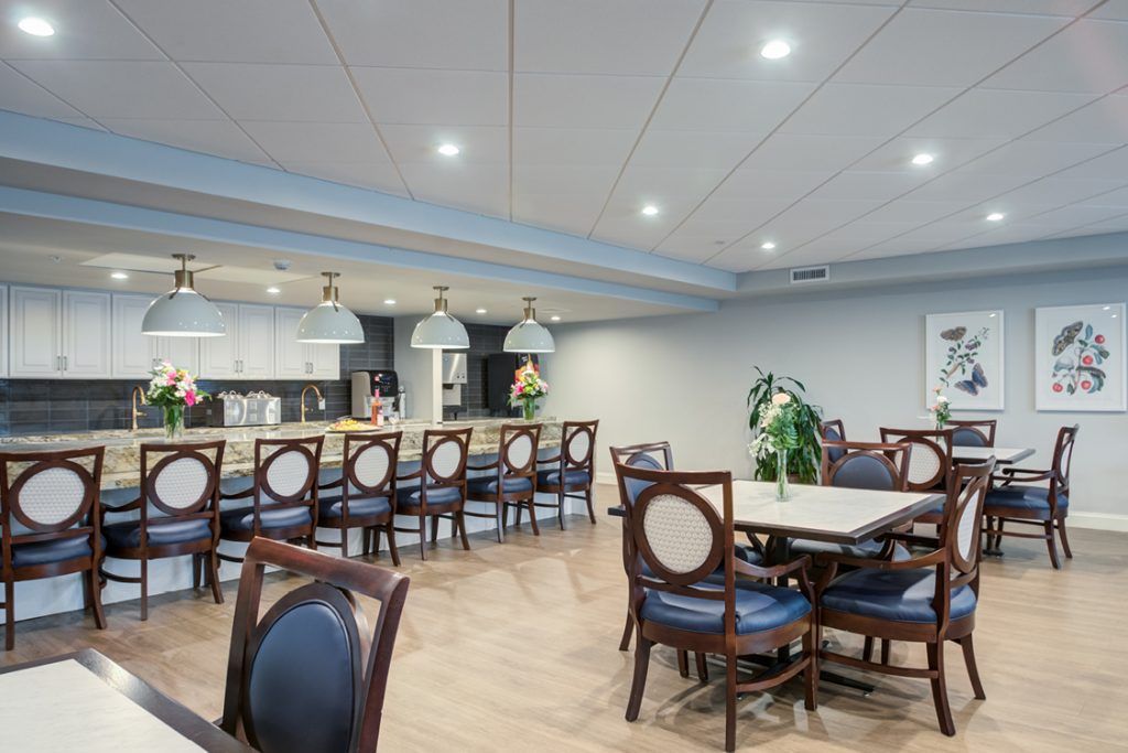 A modern dining area with tables and chairs, featuring a bar counter and contemporary lighting.