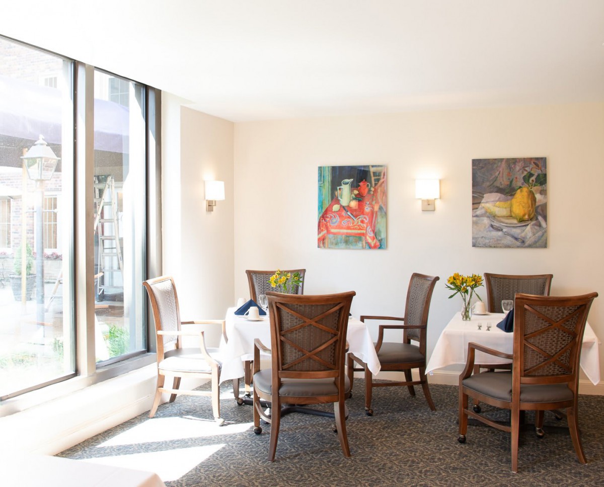 A well-lit dining area with tables and chairs, decorated with artwork on the walls.