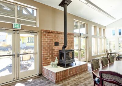 A modern indoor space featuring a central fireplace with a brick surround and large windows.