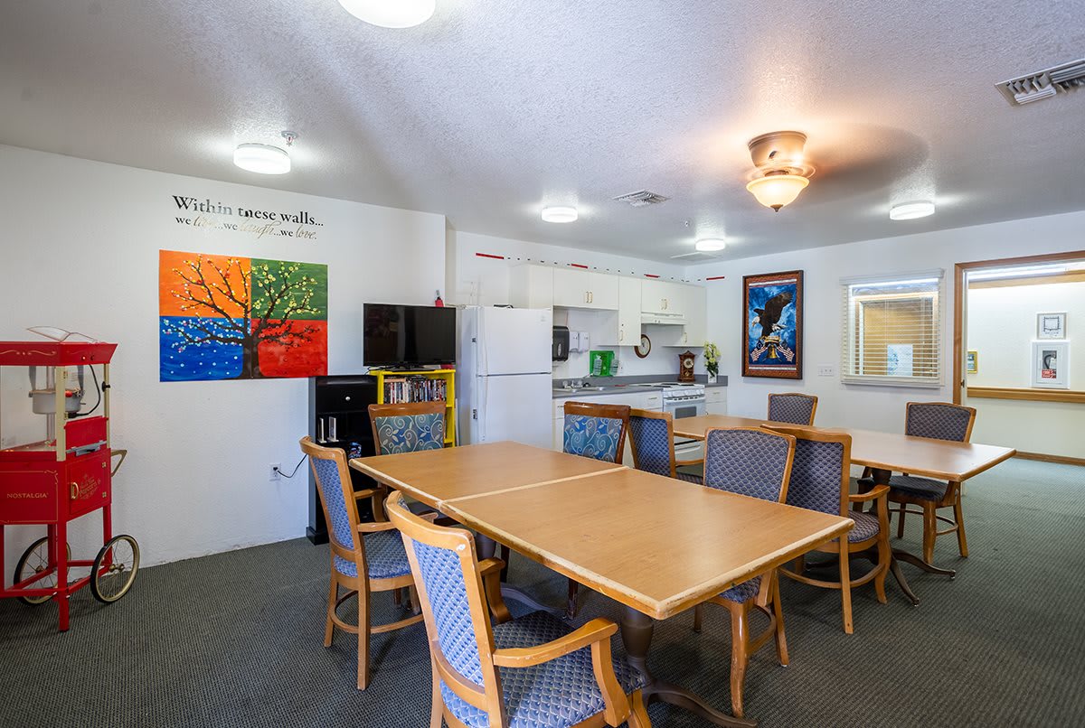 A cozy kitchen and dining area featuring wooden tables and chairs, adorned with colorful artwork on the walls.