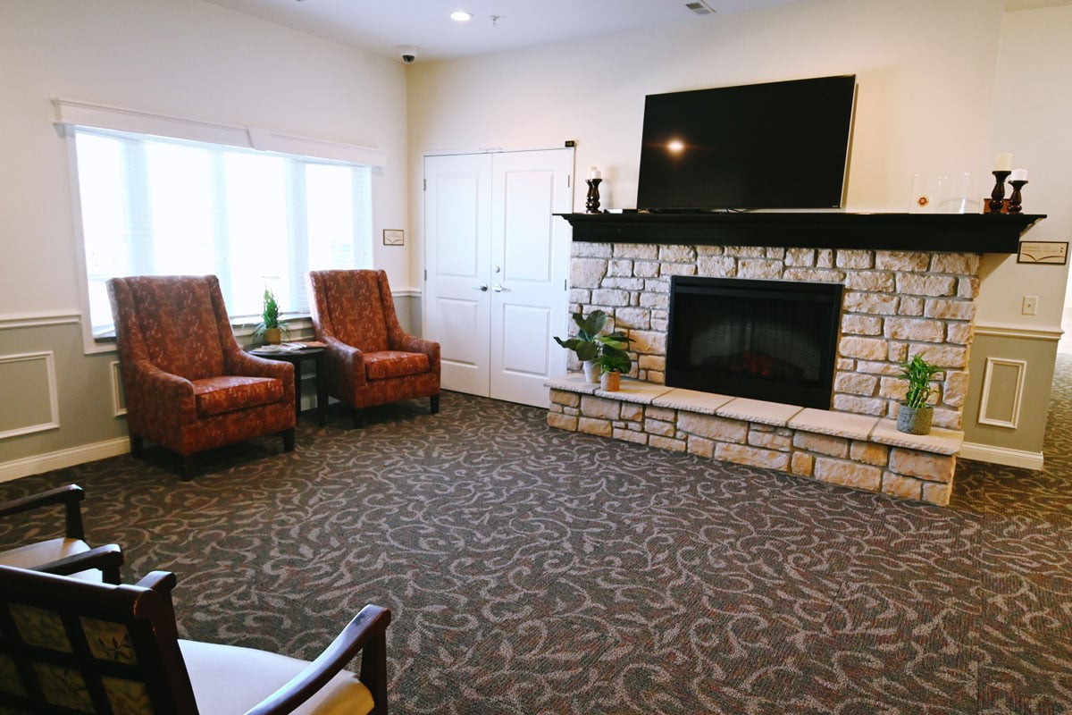 A cozy living room area featuring a stone fireplace, television, and comfortable armchairs.