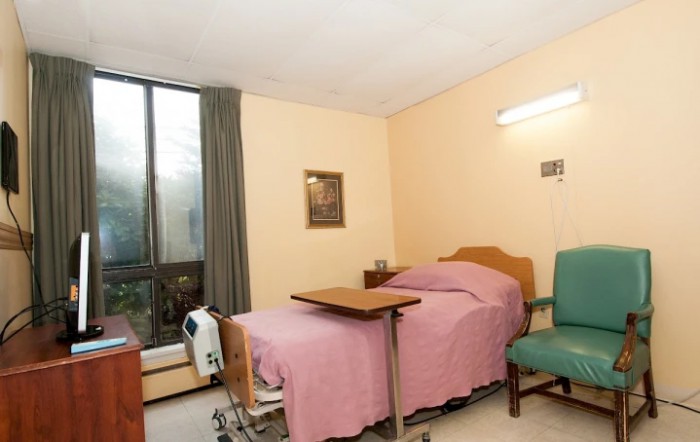 A hospital room with a bed, medical equipment, and a window with curtains.