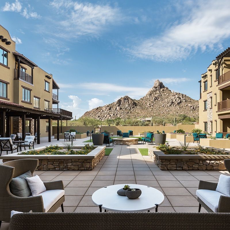 A scenic outdoor patio with seating, offering a stunning mountain view surrounded by buildings.