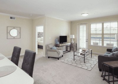 A modern living room in an apartment with neutral tones, featuring a sofa, TV, and coffee table.