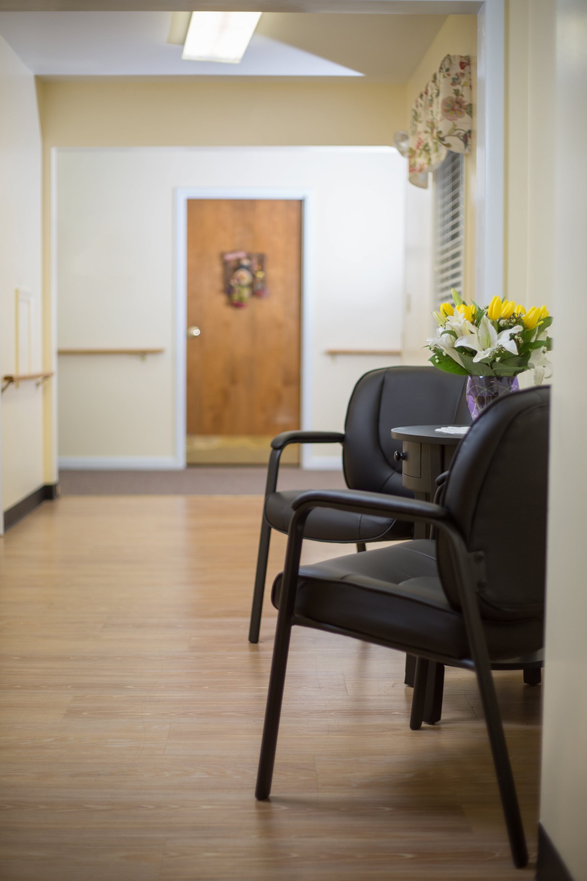 A quiet waiting area with chairs and a small table with flowers in a hallway.