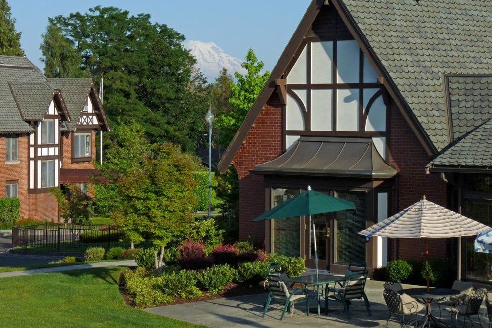 A traditional-style building with outdoor seating and a lush garden on a sunny day.