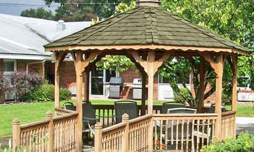 A wooden gazebo surrounded by greenery, offering a cozy outdoor space for relaxation.