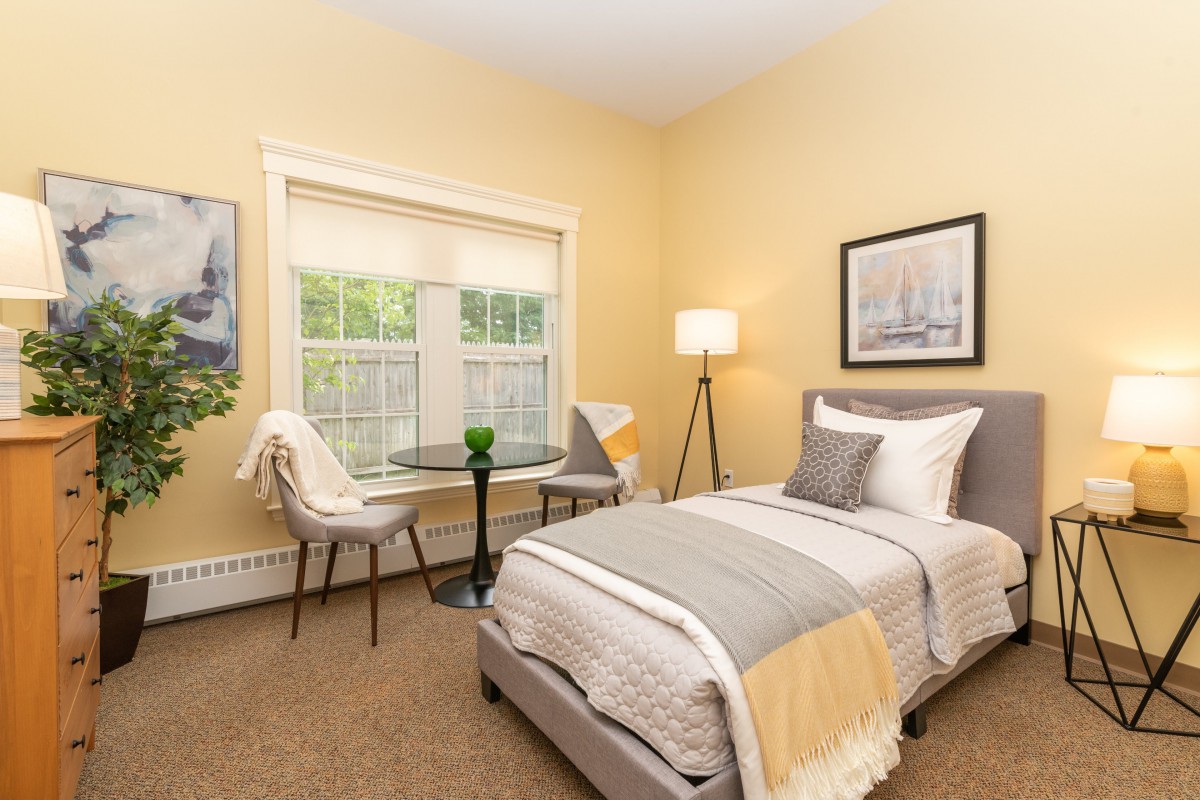 A cozy bedroom with a single bed, modern decor, and a small table by the window.