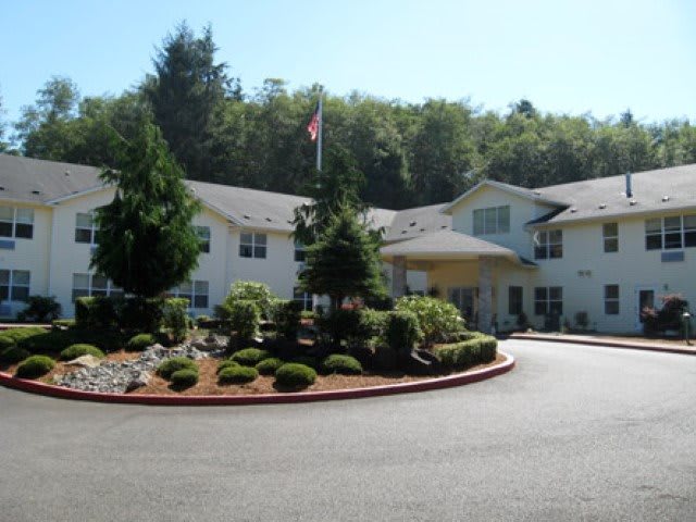 A residential building with a landscaped driveway and trees in the background.