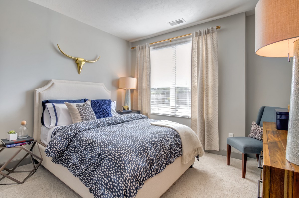 A modern bedroom with stylish decor and a large window.