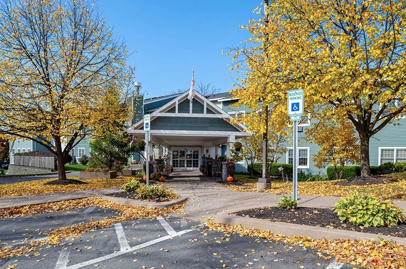 A building surrounded by trees with autumn leaves and a nearby parking lot.