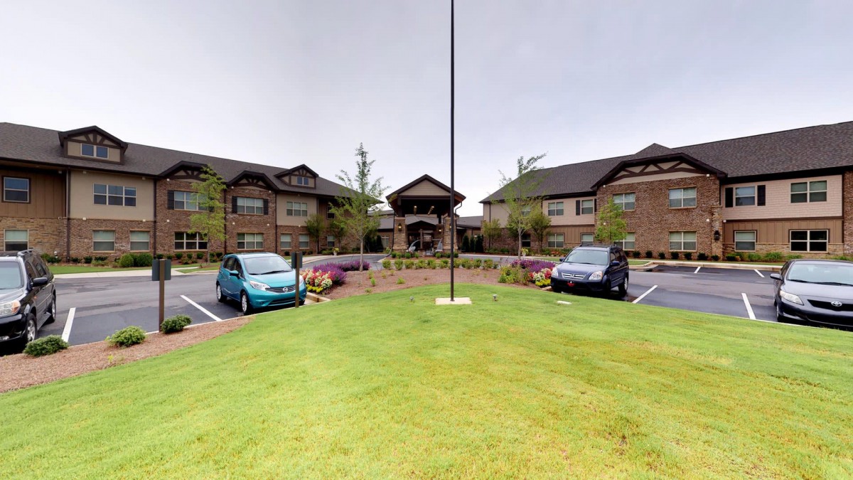 A view of a brick building with cars parked in front on a cloudy day.