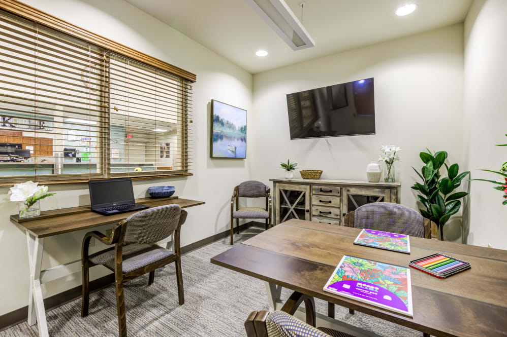 A cozy office space featuring a desk with a laptop, chairs, and decorative elements.