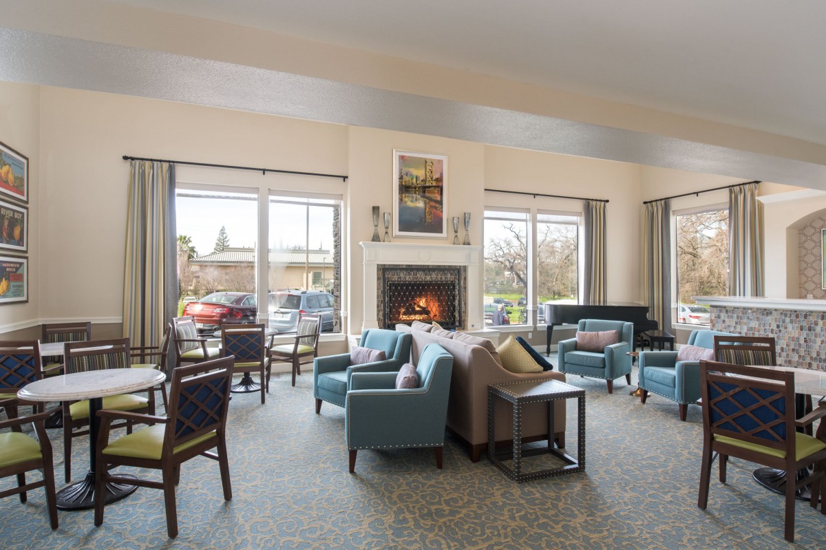 A cozy living room with a fireplace, comfortable seating, and large windows.