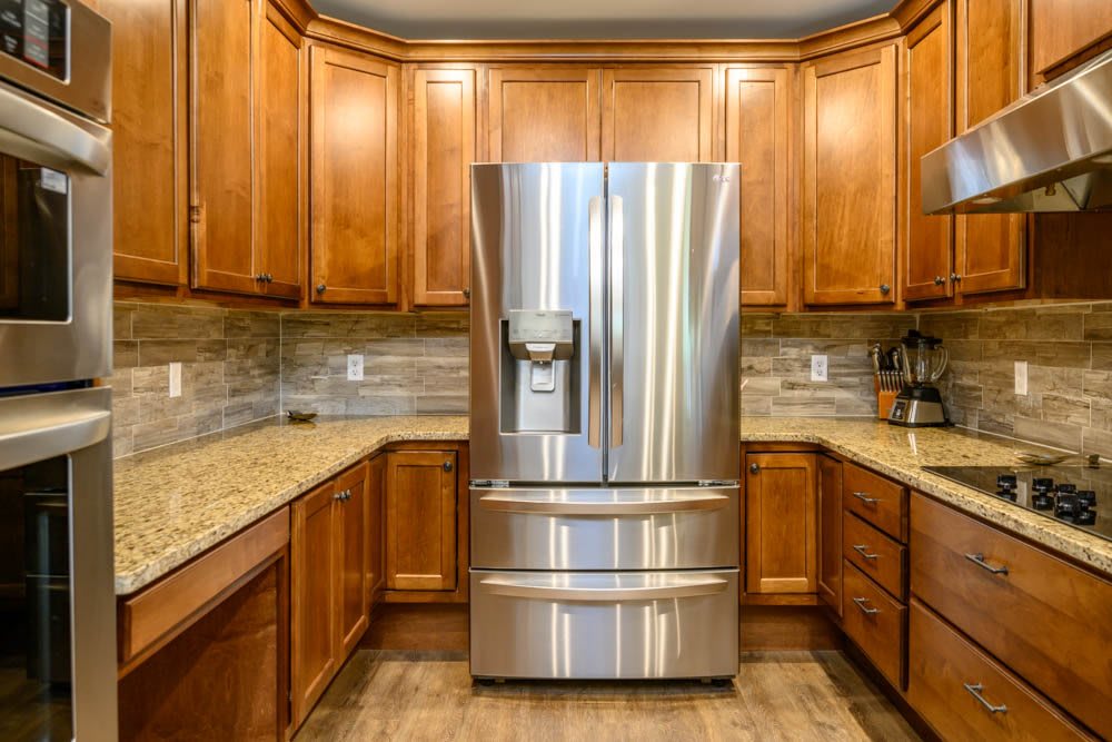 A modern kitchen featuring a stainless steel refrigerator surrounded by wooden cabinets.