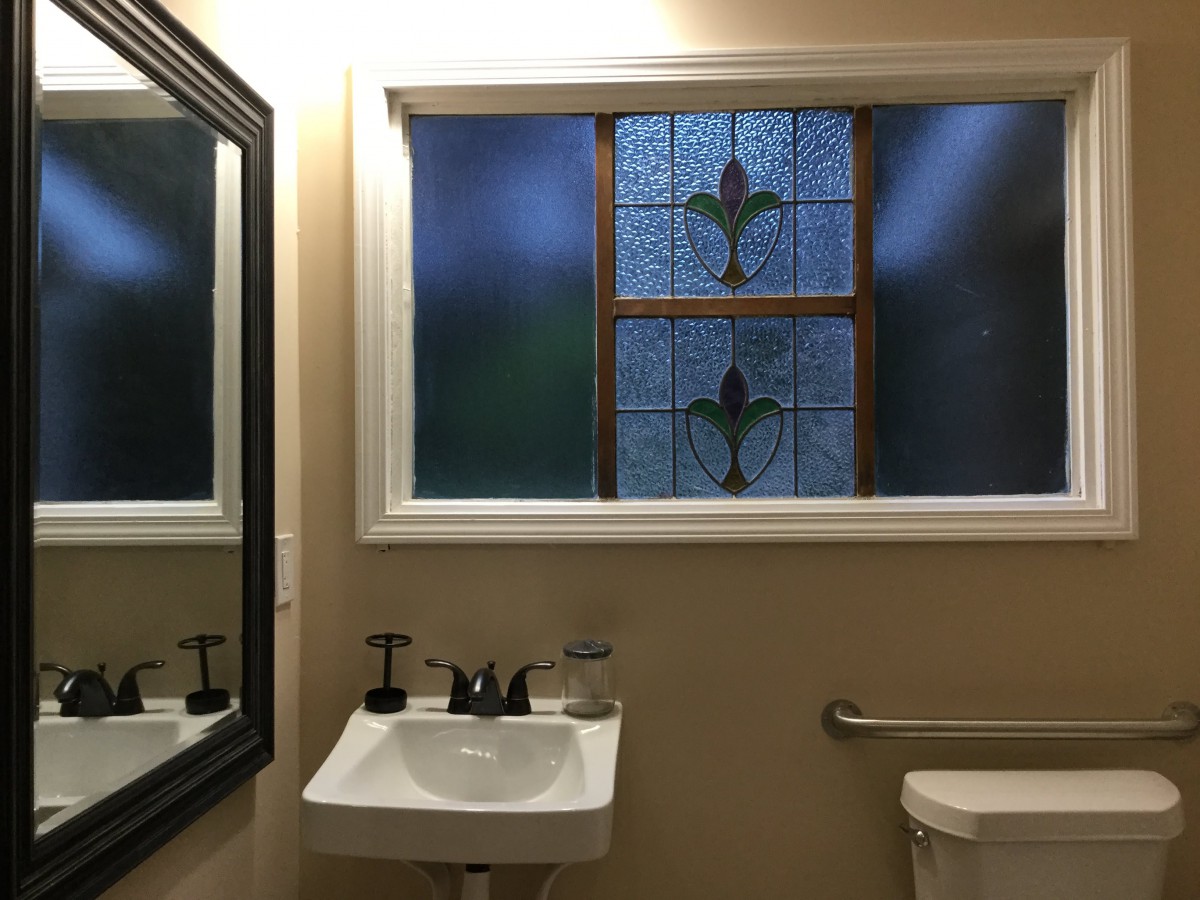 A bathroom with a stained glass window and a white sink.