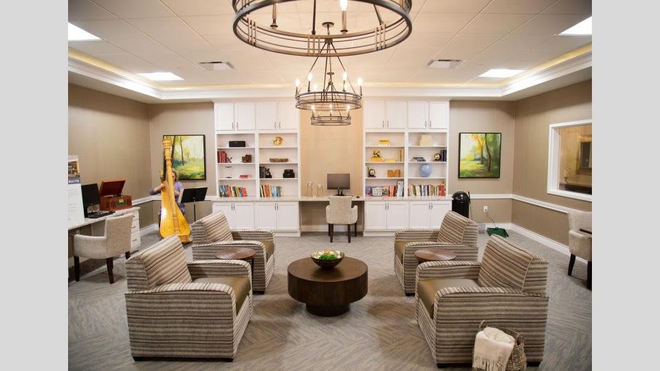 A modern living room with a central seating area, bookshelves, and a chandelier.