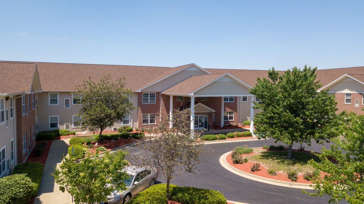 A well-landscaped building entrance with a circular driveway and surrounding greenery.