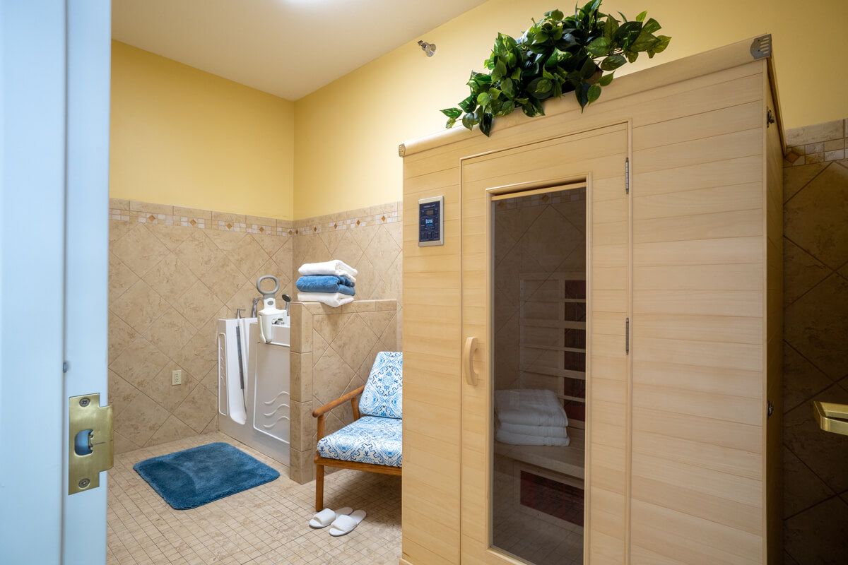 A cozy spa room featuring a wooden sauna, towels, and a comfortable seating area.