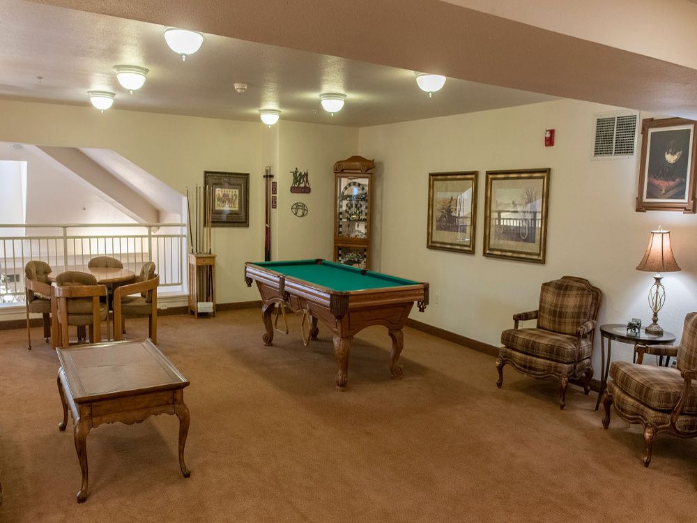 A cozy game room featuring a pool table and comfortable seating with decorative wall art.
