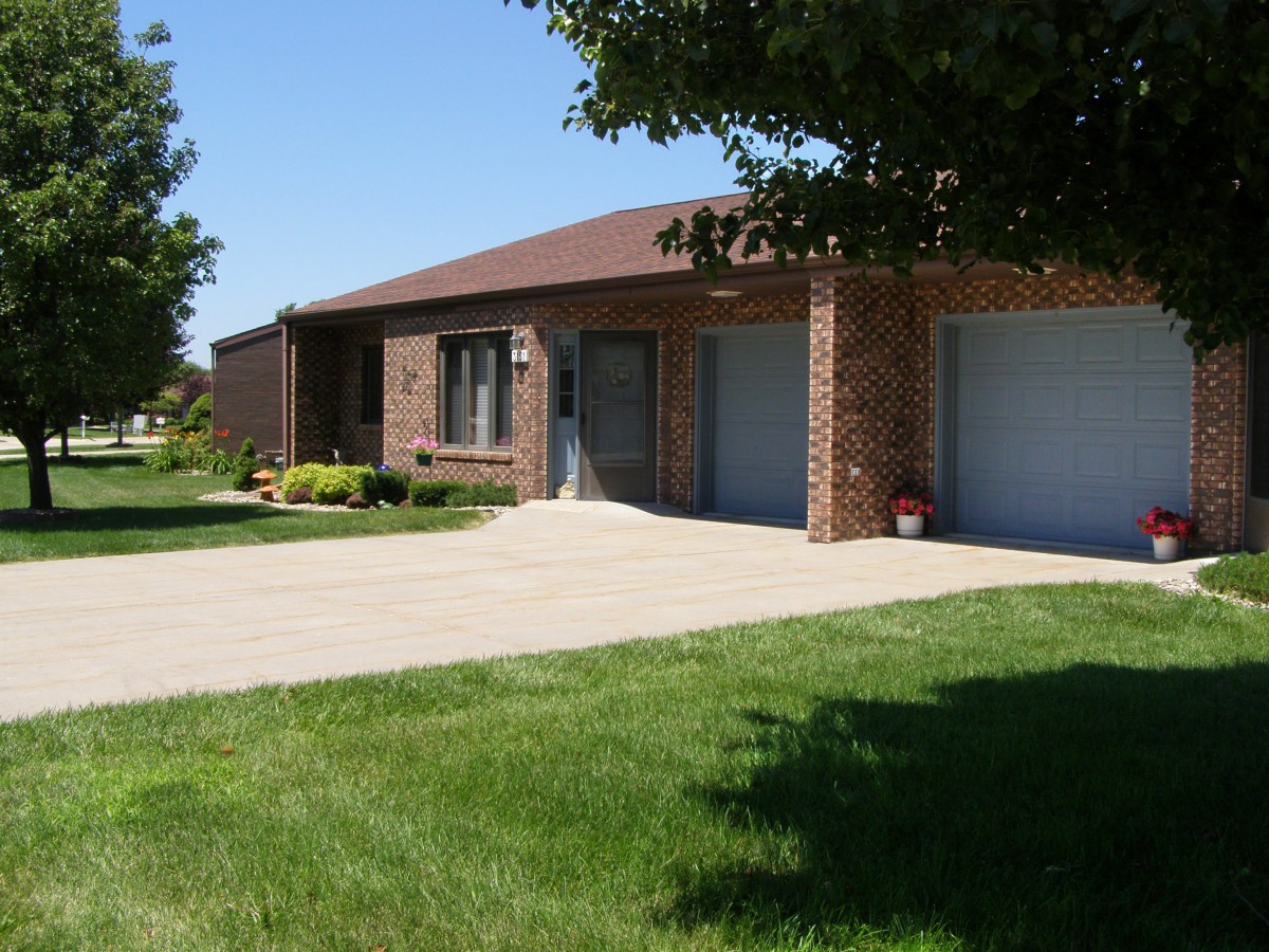 A suburban brick house with a well-maintained lawn and driveway.