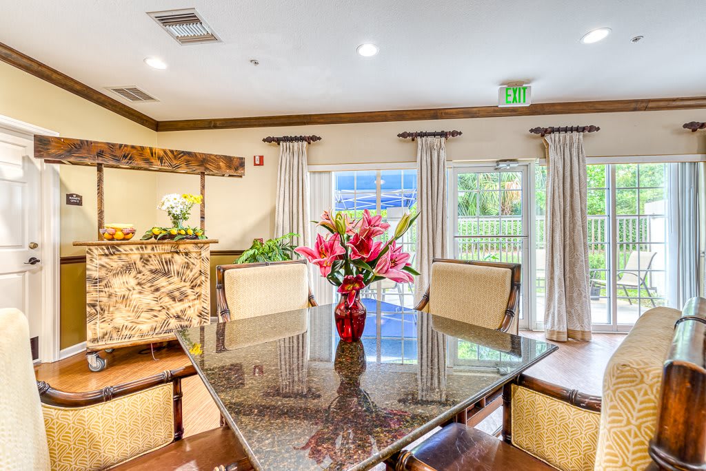 A well-decorated dining area with a central table, chairs, and a vase of flowers.