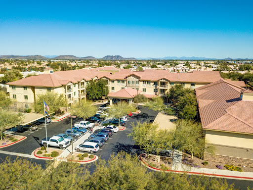 Aerial view of a modern apartment complex surrounded by green landscaping and parking.