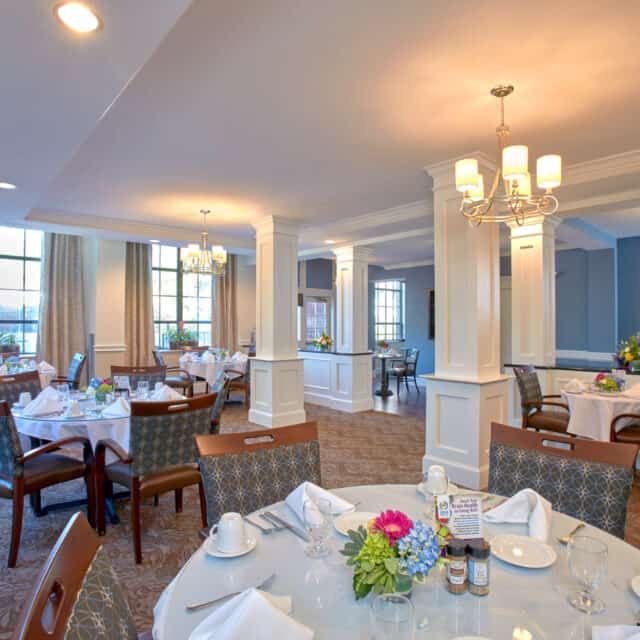 An elegant dining room with neatly arranged tables and chairs, featuring stylish lighting and decor.