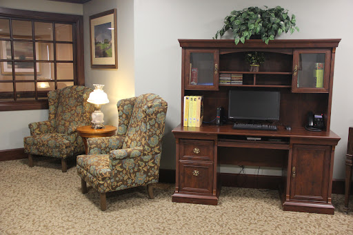 A cozy office space featuring comfortable chairs, a wooden desk with a computer station, and decorative elements.