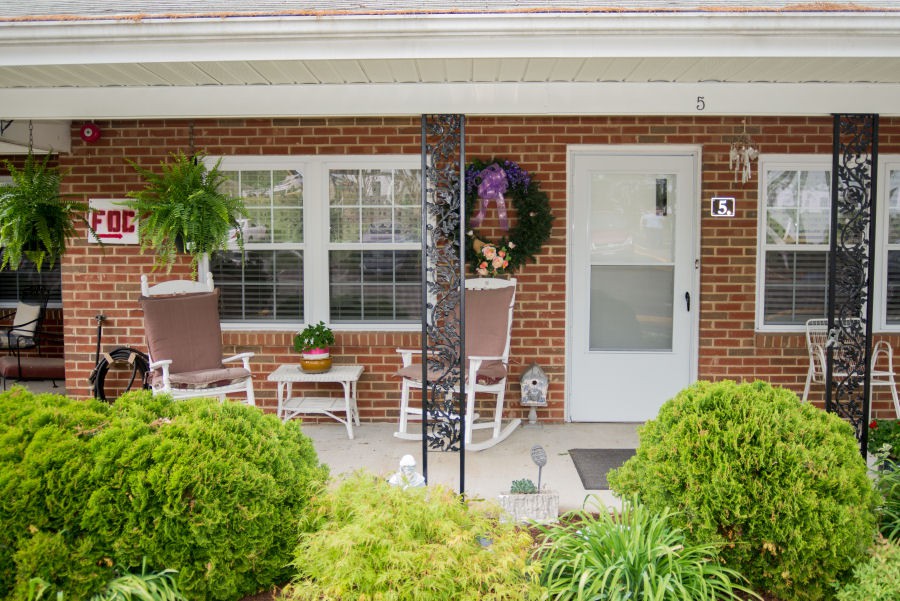 A cozy brick porch with chairs and potted plants.