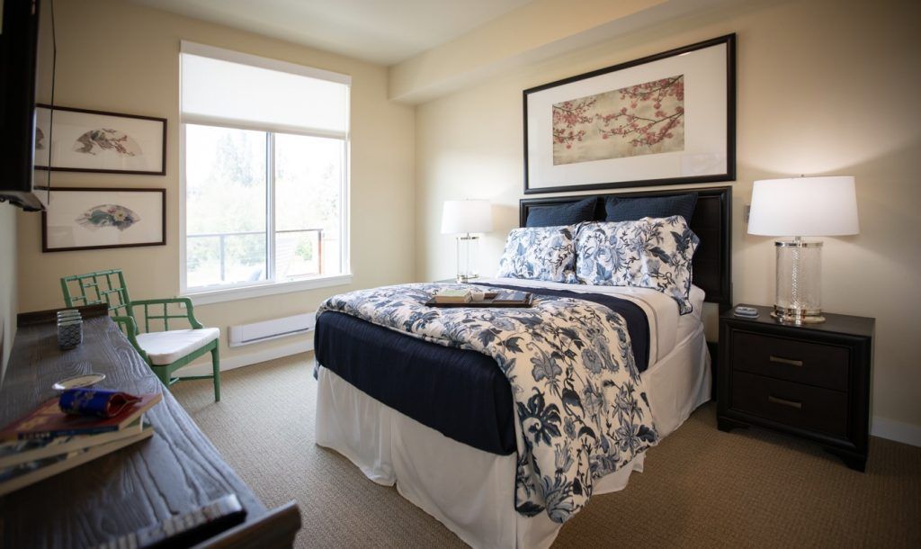 A cozy bedroom with a neatly made bed and large window providing natural light.