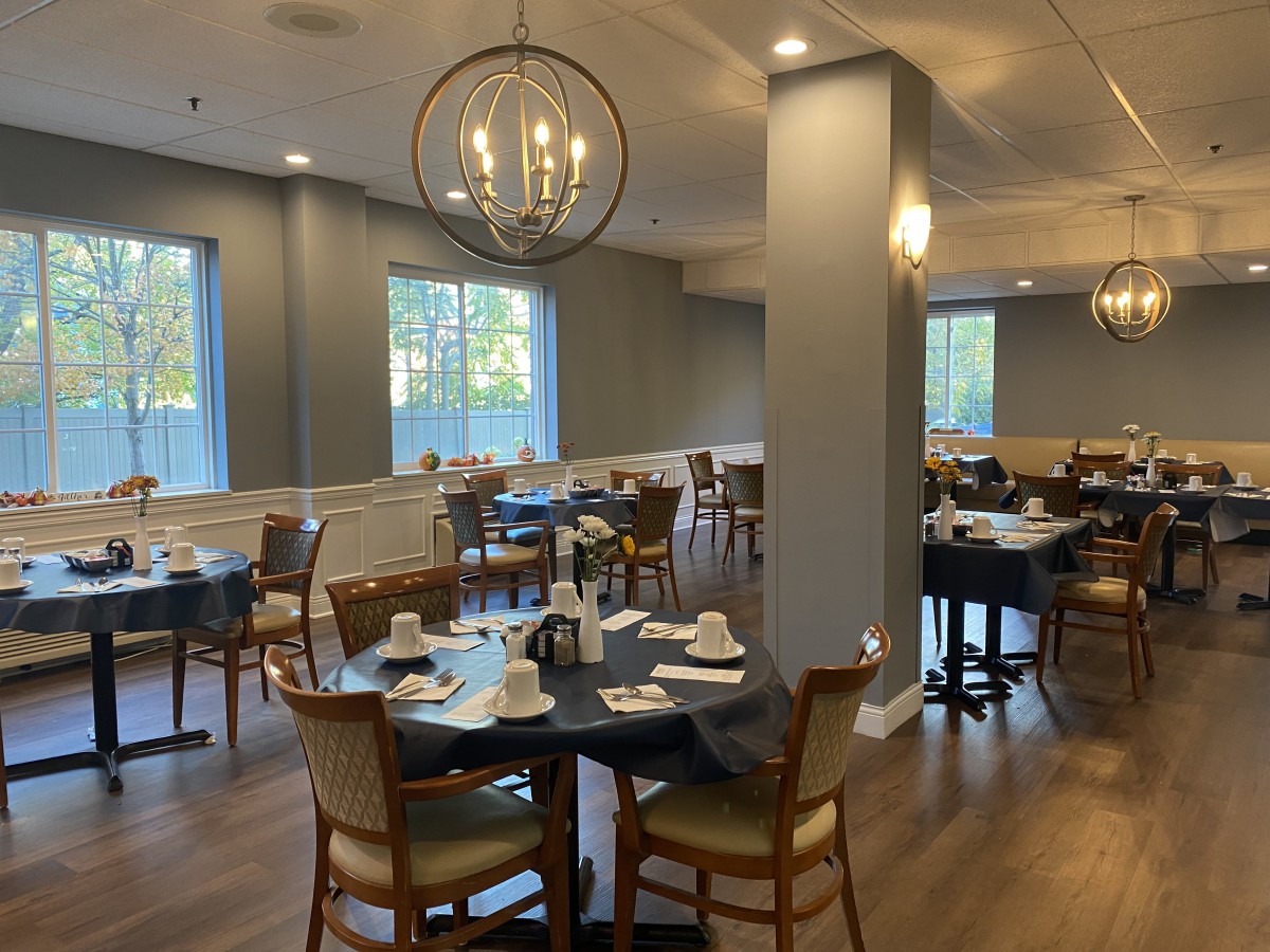 A well-lit restaurant dining area with neatly arranged tables and chairs, complemented by a stylish chandelier.