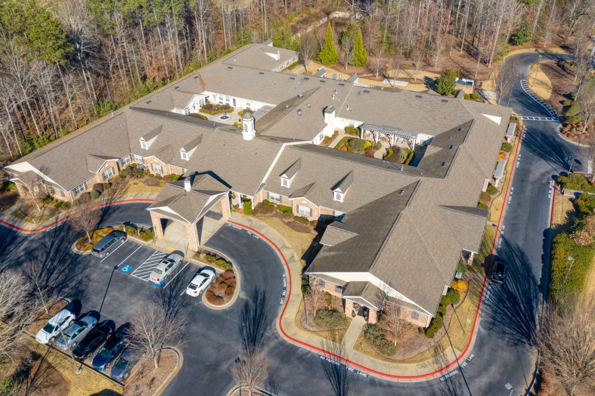Aerial view of a large building with a surrounding parking lot and trees.