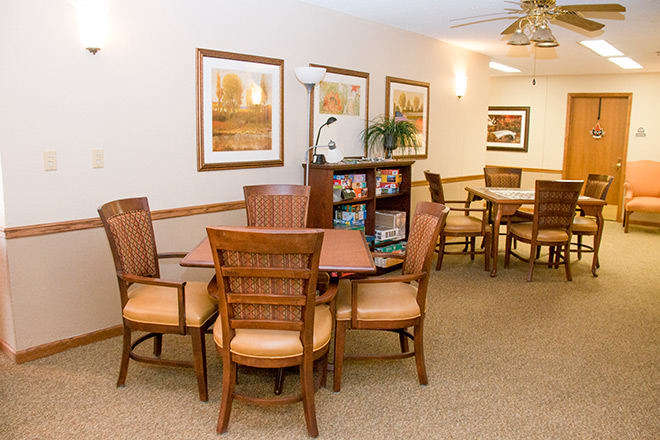 A cozy seating area featuring wooden tables and chairs, adorned with wall art and soft lighting.
