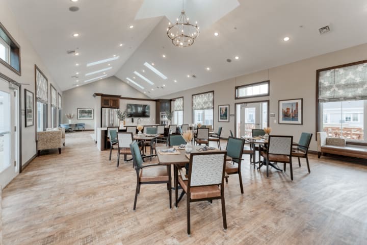A spacious and elegantly designed dining area with multiple tables and chairs, featuring modern decor and ample natural lighting.