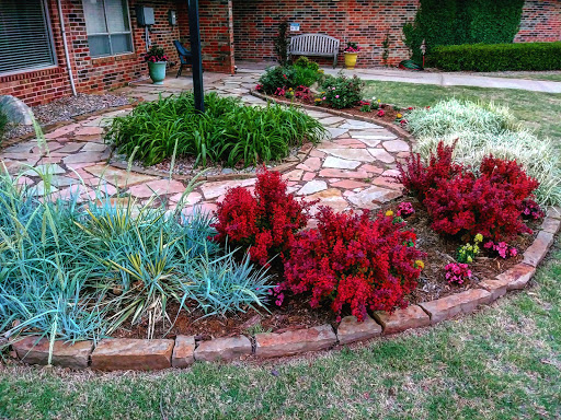 A beautifully landscaped garden featuring vibrant red plants and a stone pathway.