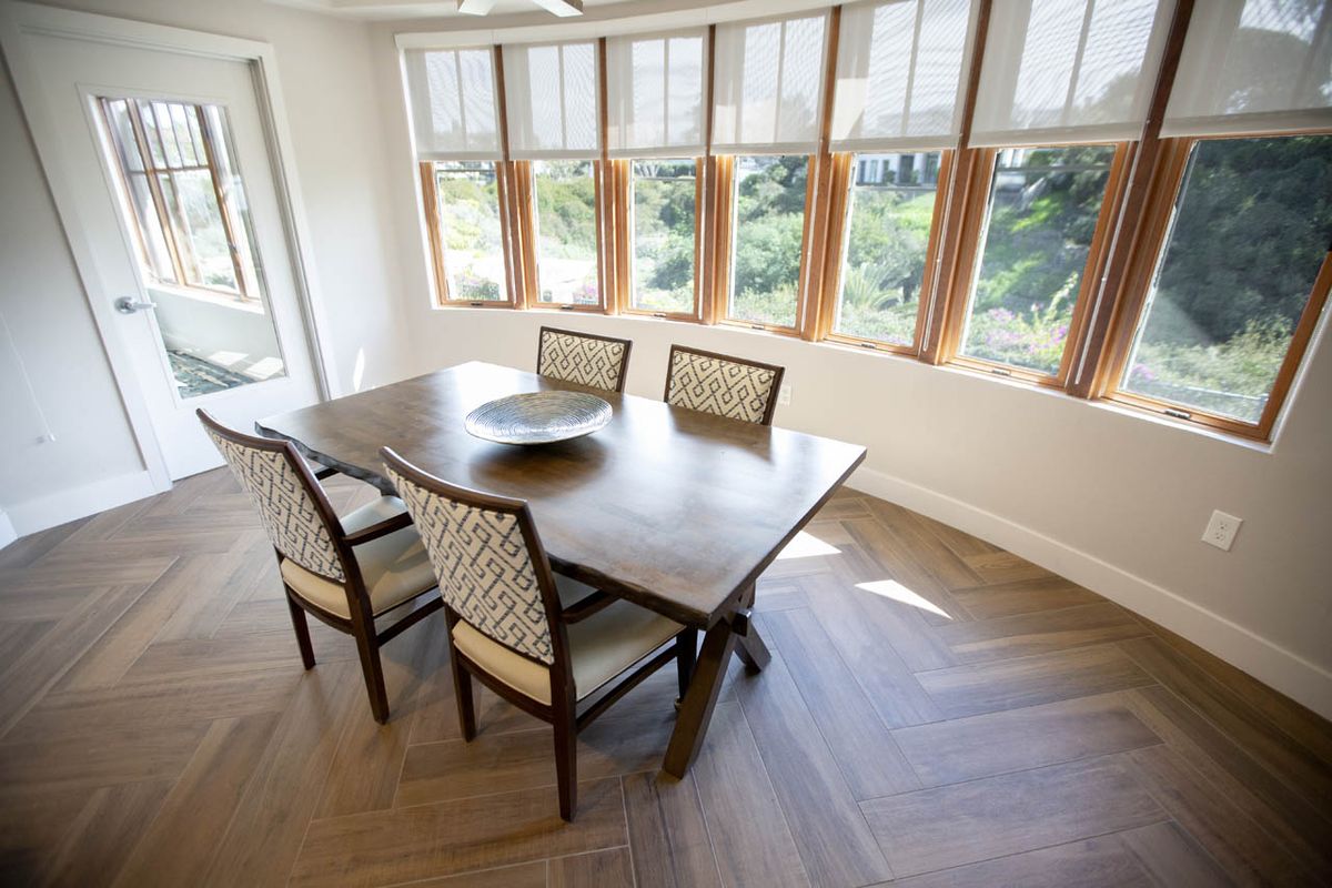 A bright dining area with a wooden table and chairs surrounded by large windows.