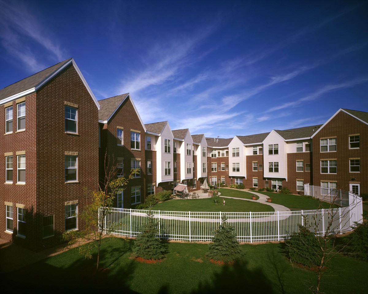 A view of a modern apartment complex with brick buildings and landscaped surroundings under a clear blue sky.