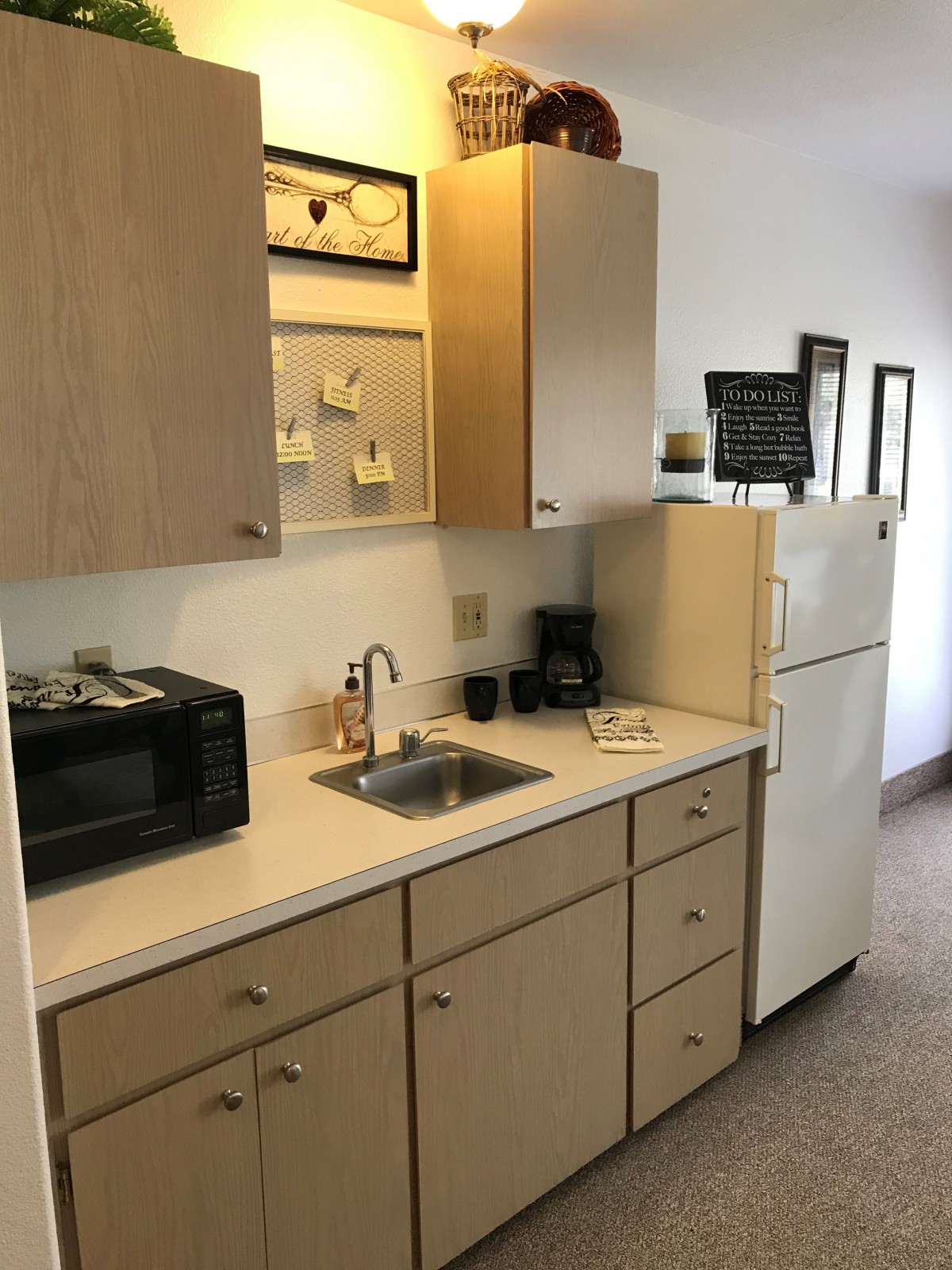 A small kitchen area featuring a microwave, sink, and refrigerator.