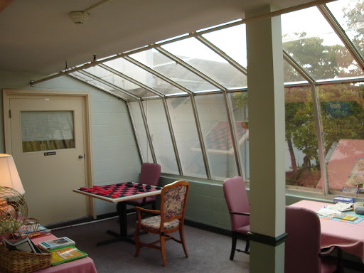 A cozy sunroom with a glass ceiling, featuring tables and chairs for relaxation.