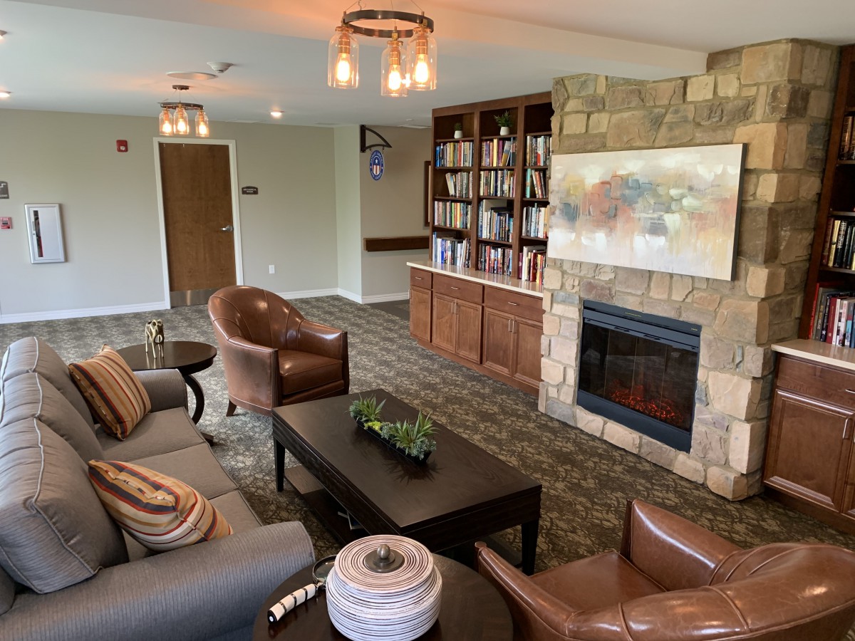A cozy living room with a stone fireplace and built-in bookshelves, featuring leather chairs and a comfortable sofa.