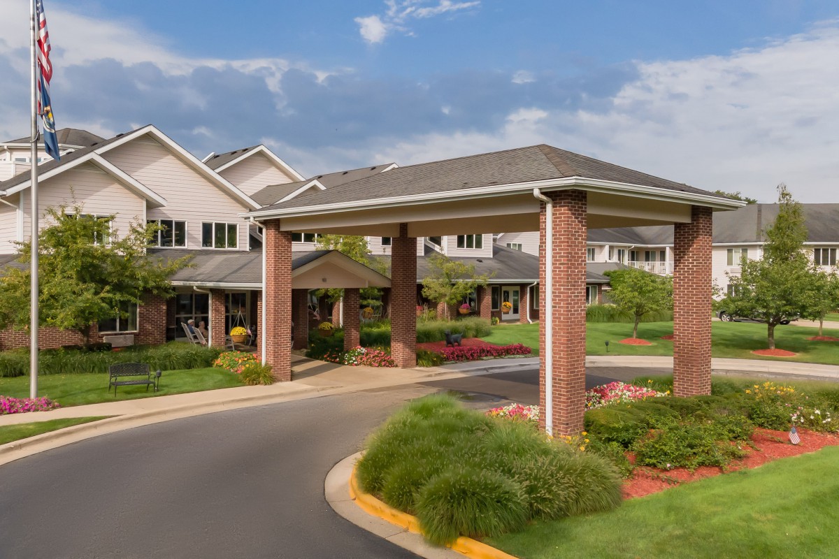 Entrance of a residential building with landscaped surroundings and a covered driveway.