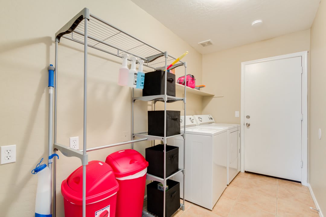 A well-organized laundry room with a washing machine, dryer, and shelving units for storage.