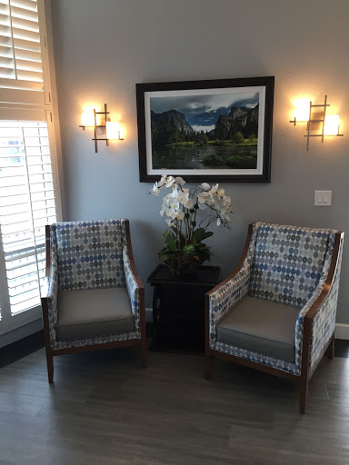 A cozy corner featuring patterned chairs, a decorative plant, and artwork on the wall.