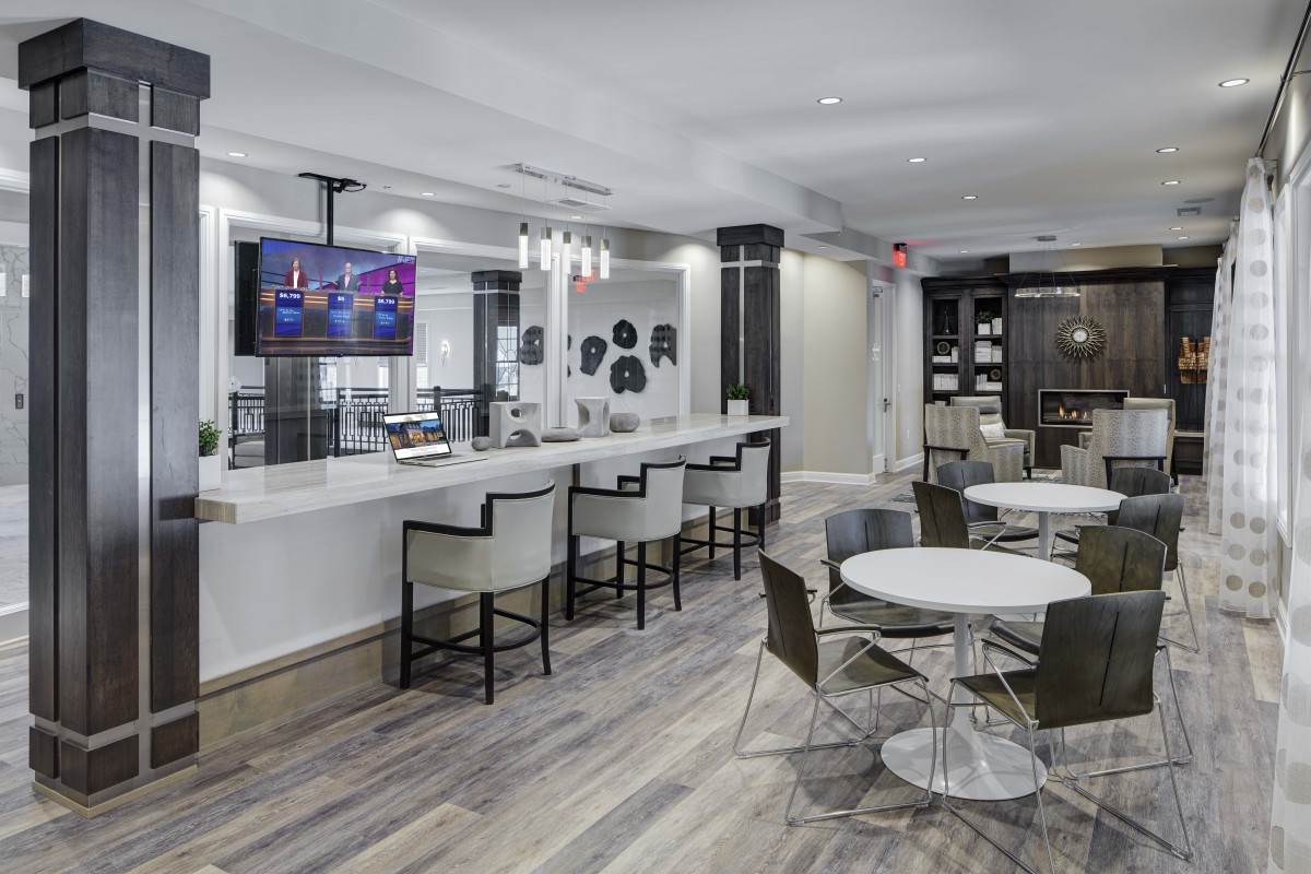 A modern lounge area with a bar, seating, and a television on the wall.