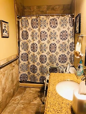 A cozy bathroom featuring a decorative shower curtain and a neatly arranged sink area.